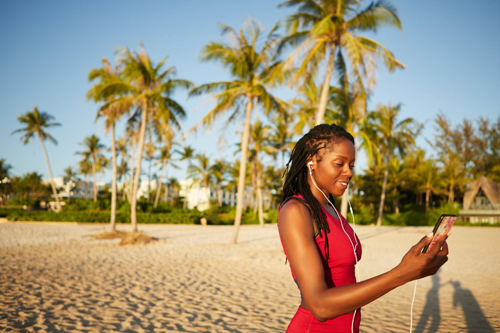 woman on the beach with headphones on and palm tress in the background