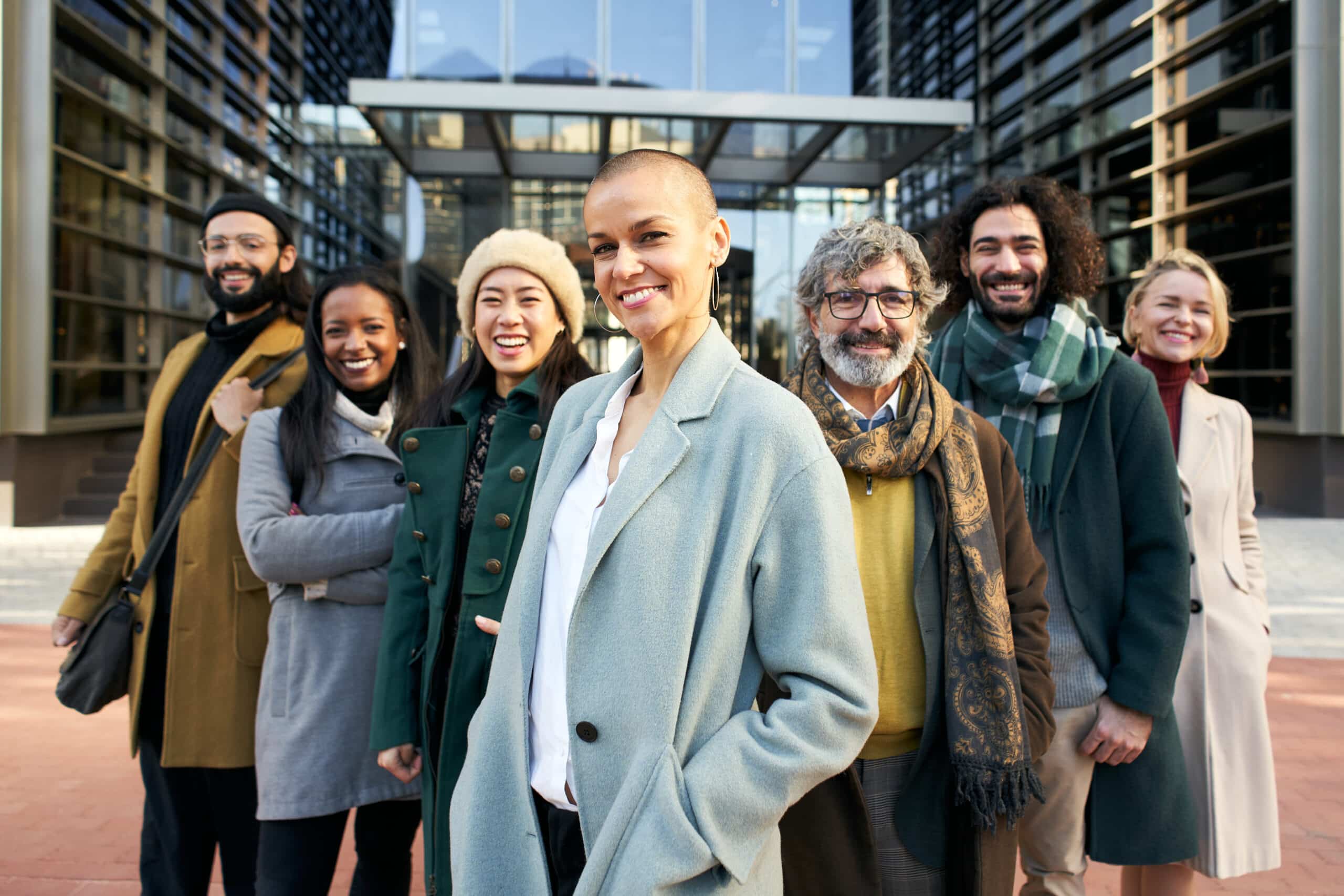 A group of smiling business people from a company led by an empowered shaved air woman Cheerful Looking at camera portrait of a group of happy co-workers of diverse races and ages