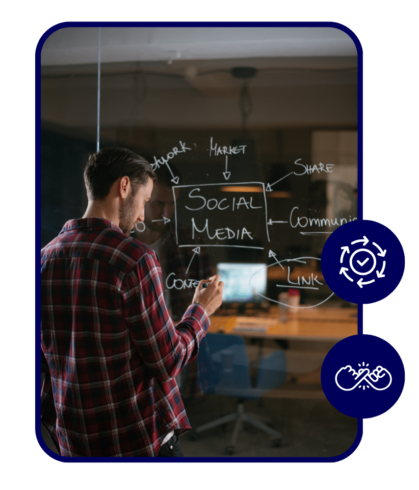 Man in a plaid shirt writing a social media strategy diagram on a glass wall in an office, with arrows pointing to words like market, share, content, and communication.