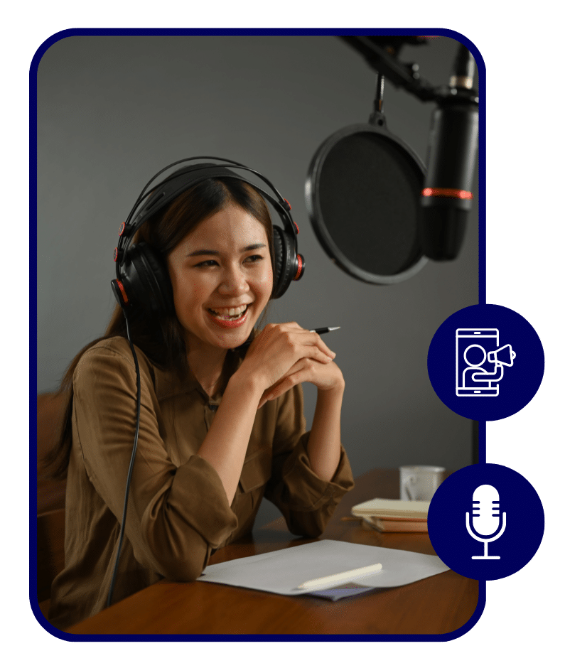 Smiling woman wearing headphones and speaking into a microphone while recording a podcast, with papers and a pen on the desk in front of her.