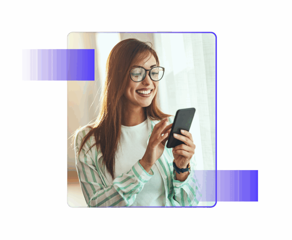 Smiling woman wearing glasses and a striped shirt uses her smartphone near a window.